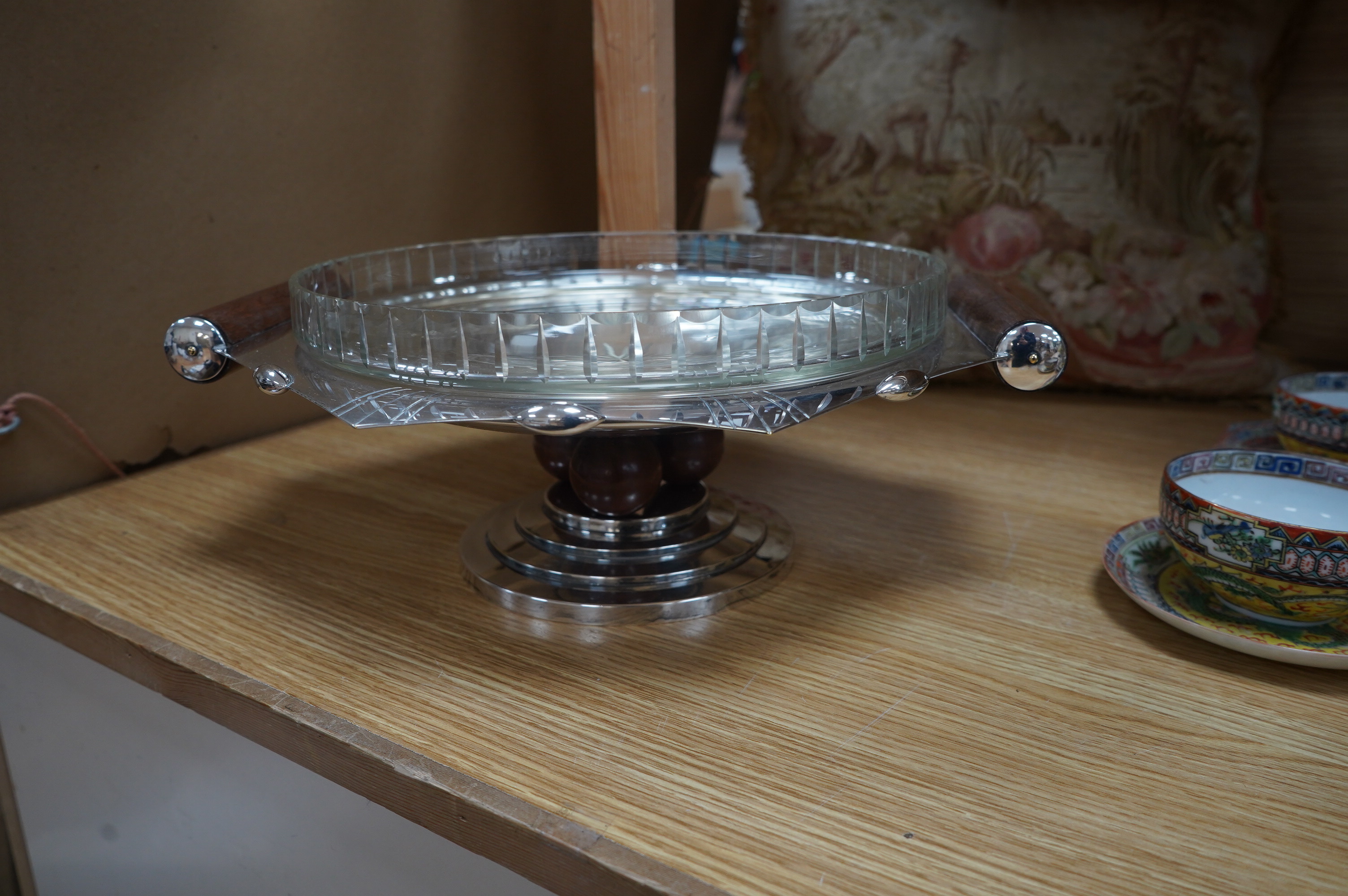 A French Art Deco silver plated and glass comport, with wood handles, set on three wooden spheres above a stepped plated base, 36cm wide, 13.5cm high. Condition - good